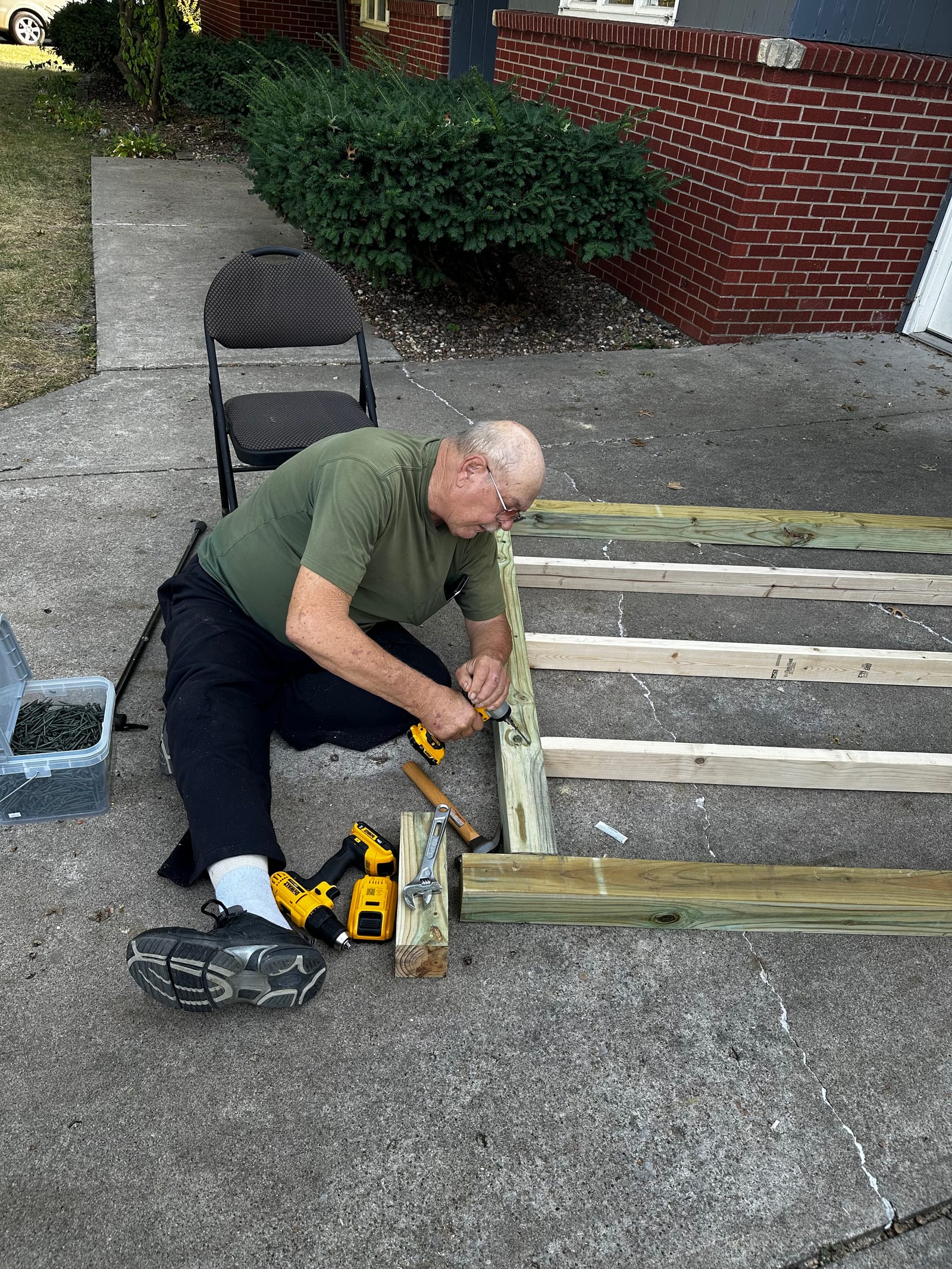 Ben's dad, seated, driving screws into the frame.